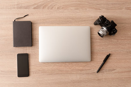 Minimalist freelance traveler photography equipment. A digital camera, laptop, cell phone and a notebook on a wooden desktopの写真素材