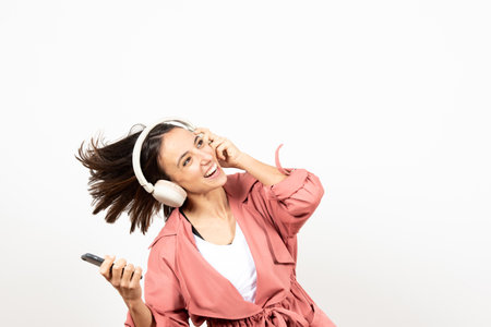 Happy latin woman with headphones dancing and looking to white copy space.の写真素材