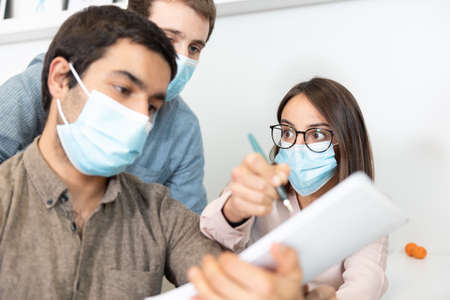 Coworkers wearing face masks contrasting opinions at the workplace. Working in the office during ...