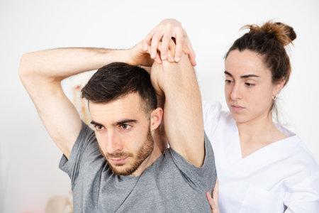 Female physiotherapist treating and stretching a patient in a rehabilitation centerの写真素材