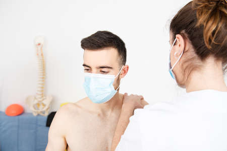 Physiotherapist working on the rehabilitation of a patient wearing a face mask during Coronavirus pandemicの写真素材