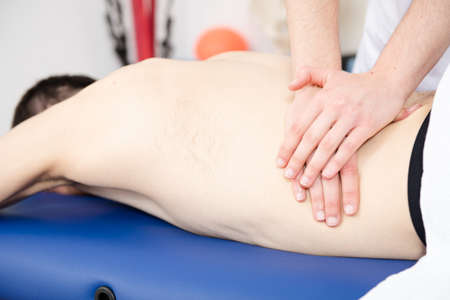 Closeup view of a physiotherapist massaging the back and waist of a patient.
