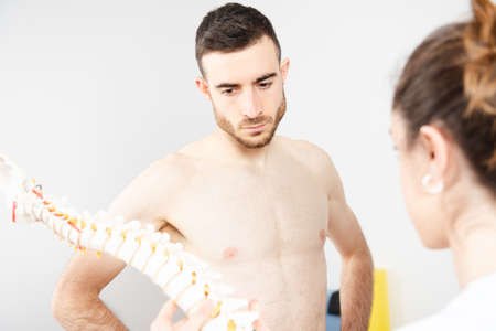 Shirtless athletic patient paying attention of the explanation of a physiotherapistの写真素材