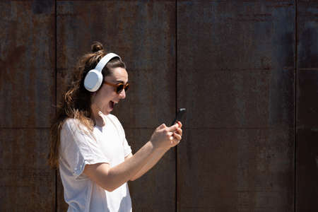Happy woman receiving good news on her phone isolated on oxidized metallic wall.の写真素材