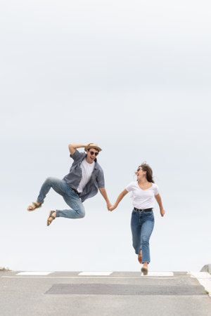 Happy couple running and jumping on the road, celebrating success. Happiness concept with minimalist...