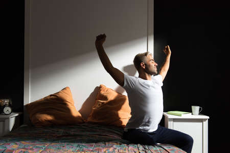 Hispanic man stretching out in his bedroom. Morning routine conceptの写真素材