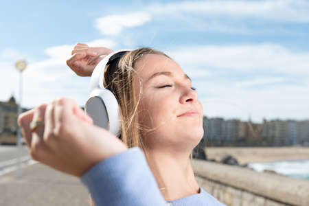 Closeup of young woman listening to music on headphones and dancing.