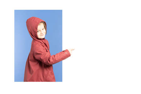Little cute girl wearing a raincoat pointing to copy space.
