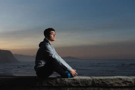 Hispanic teenager tying sport shoes at seaside