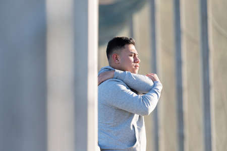Young focused man stretching arms