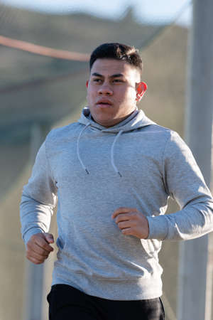 Young latin man running while thinking on his goals. Losing weight concept.