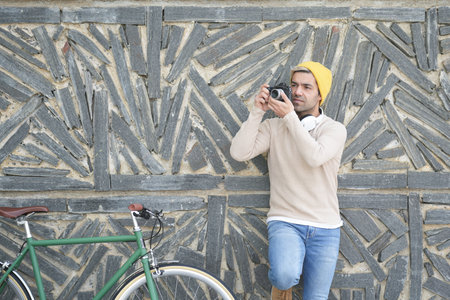 Hispanic content creator against wall taking a photograph
