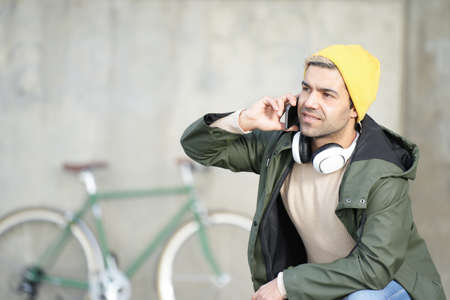 Hispanic man talking on phone with his bicycle in the background.の写真素材