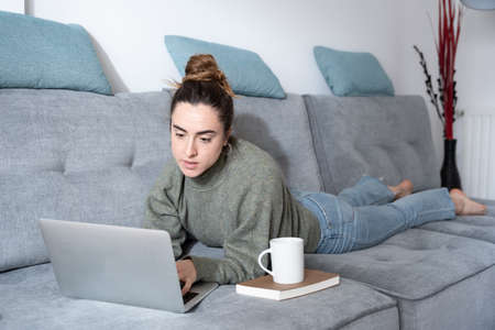 Young blogger creating content for social media while lying on couch.