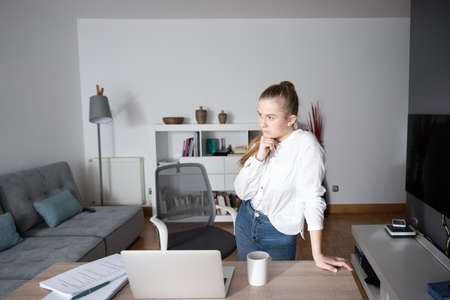 Working from home and freelancing concept. Young woman standing and thinking on project in front of...