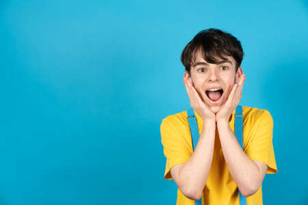 Cute surprised teenager with blue copy space.の写真素材