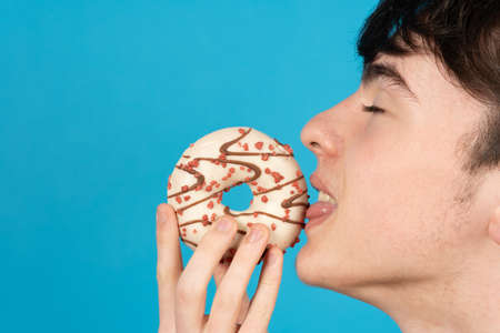 Closeup of boy licking chocolate sweet bun or cupcake.