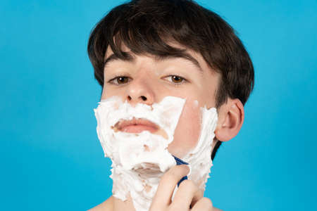 Closeup portrait of teenager boy shaving his face for the first time.の写真素材