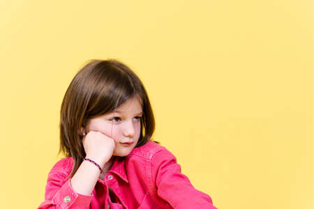Sad little girl looking at yellow copy space