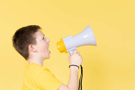 Cute boy shouting on megaphone to copy space. Children's rights concept.の写真素材