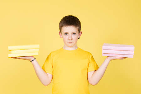 Boy holding books on hands as a school punishment. Child choosing subject to studyの写真素材