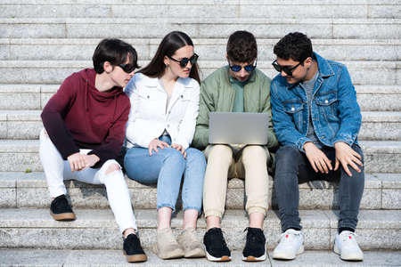 Group of teenager students sitting on stairs and working together.