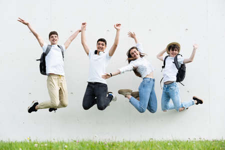 Happy group of teenager students jumping and celebrating while looking at camera.の写真素材