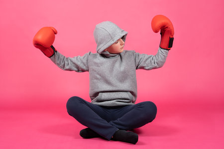 Teenager boy wearing boxing gloves looking at biceps. Growth during adolescence conceptの写真素材
