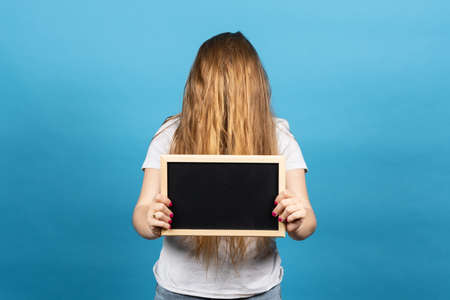 Woman covering face with long hair and holding blackboard. Hairdressing advertising conceptの写真素材