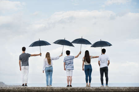 Teamwork and sacrifice concept. Group of people covering each other with umbrellas