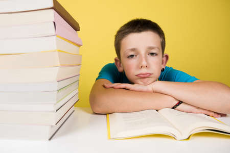 Sad and bored schoolboy looking at camera isolated on yellow background. Demotivation at school concept.の写真素材