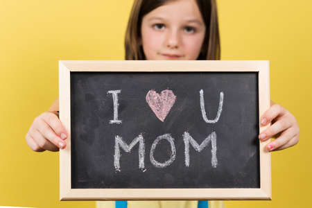 I love you mom message written on blackboard by little girl. Mother's day concept.の写真素材