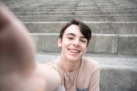 Positive cute teenager boy taking selfie in grandstand. Teenager smiling and looking at camera.