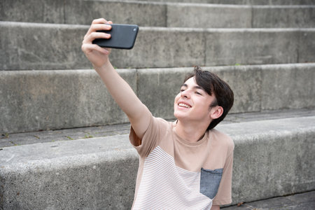 Smiling teenager boy taking selfie in a grandstandの写真素材