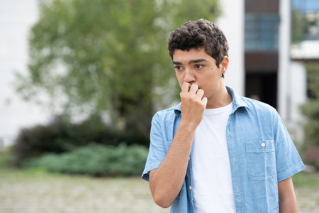 Worried and concerned hispanic boy thinking hand on mouth.の写真素材