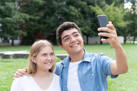 Cheerful teenager couple taking selfie in a parkの写真素材