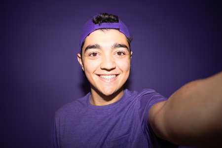 Hispanic teenager boy taking selfie isolated on purple backgroundの写真素材