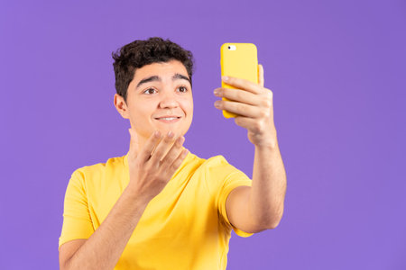 Hispanic influencer boy live streaming and talking on phone isolated on purple backgroundの写真素材