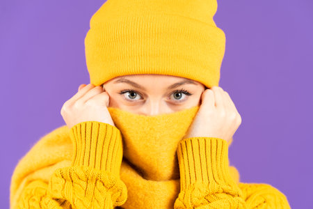 Portrait of winter clothing woman looking at camera isolated on purple backgroundの写真素材