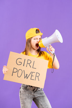 Little protestor kid showing girl power message on a cardboard isolated on purple backgroundの写真素材