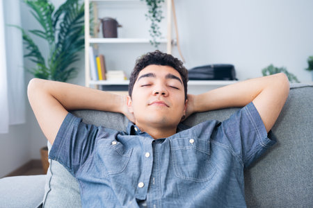 Closeup of hispanic teenager boy resting and relaxing with closed eyes and hands behind headの写真素材