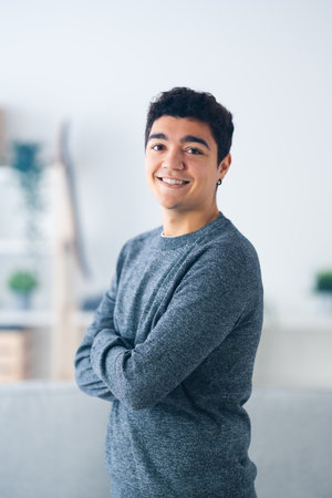 Portrait of standing handsome hispanic teenager boy smiling at camera with shallow depth of fieldの写真素材