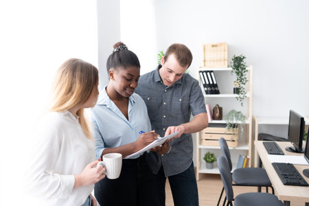 Multiethnic coworkers working together on a project standing in the office.