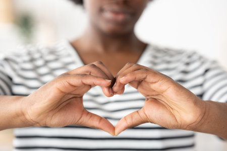 Closeup of african female hands making love sign or heart shapeの写真素材