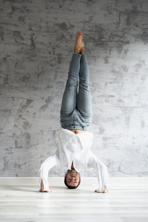 Hispanic young man doing acro yoga exercise indoors.