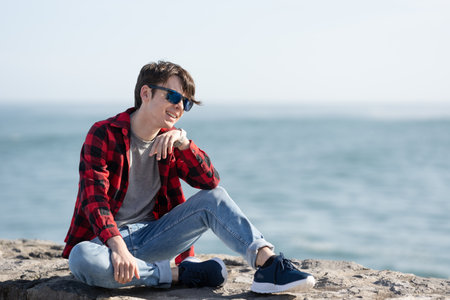 Handsome teenager boy talking on smartwatch outdoorsの写真素材