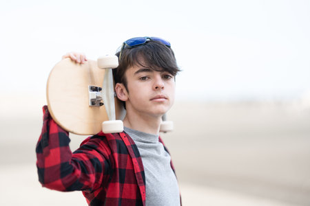 Portrait of teenager boy holding skateboard on back. Adolescence hobbies conceptの写真素材