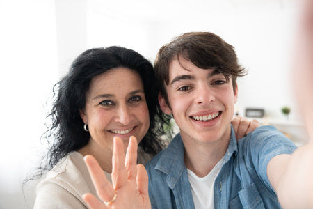 Mother and son having video call on phone. Camera point of view of woman and teenager boy live streaming.の写真素材