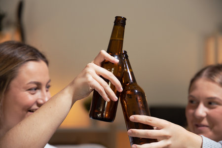 Closeup of two women toasting with beer bottlesの写真素材