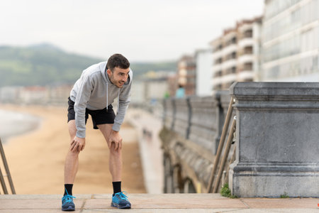 Exhausted sportsman resting during training. Perseverance concept. Tired runner outdoors.